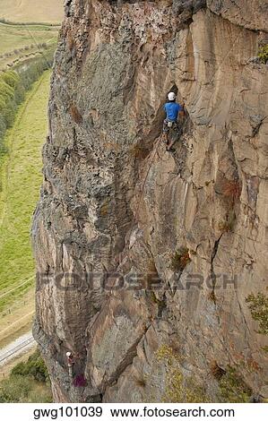 Rear view of a male rock climber ascending a steep rock View Large Photo Image Stock Photo - Rear view of a male rock climber ascending a steep rock. Fotosearch