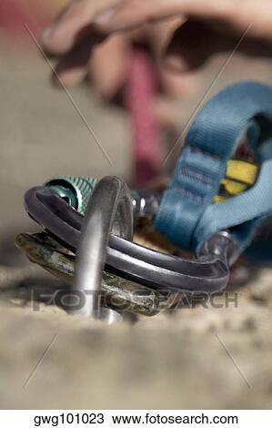 Stock Image - Rock climber concording a carabiner with a hook. Fotosearch