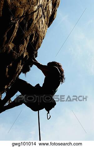 Picture - Silhouette of a female rock climber scaling a rock face. Fotosearch