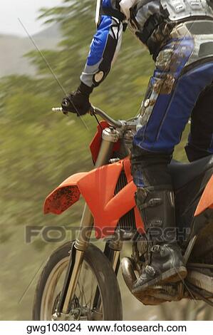 Low angle view of a motocross rider riding a motorcycle View Large Photo Image Picture - Low angle view of a motocross rider riding a motorcycle. Fotosearch