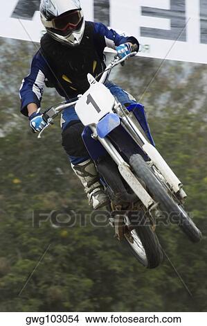Low angle view of a motocross rider performing a jump on a motorcycle View Large Photo Image Picture - Low angle view of a motocross rider performing a jump on a motorcycle. Fotosearch