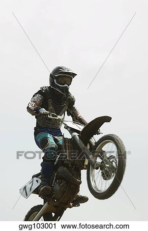 Low angle view of a motocross rider performing a jump on a motorcycle View Large Photo Image Stock Image - Low angle view of a motocross rider performing a jump on a motorcycle. Fotosearch