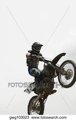 Low angle view of a motocross rider performing a jump on a motorcycle View Large Photo Image Stock Image - Low angle view of a motocross rider performing a jump on a motorcycle. Fotosearch