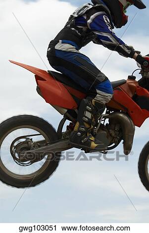 Low angle view of a motocross rider performing a jump on a motorcycle View Large Photo Image Stock Image - Low angle view of a motocross rider performing a jump on a motorcycle. Fotosearch