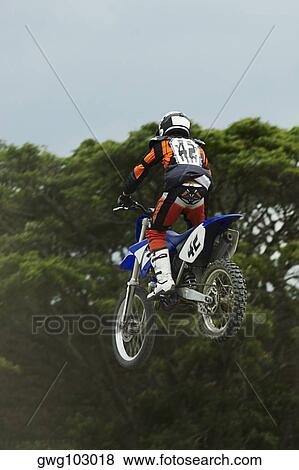 Low angle view of a motocross rider performing a jump on a motorcycle View Large Photo Image Stock Photo - Low angle view of a motocross rider performing a jump on a motorcycle. Fotosearch