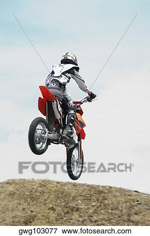 Low angle view of a motocross rider performing a jump on a motorcycle View Large Photo Image Stock Photo - Low angle view of a motocross rider performing a jump on a motorcycle. Fotosearch