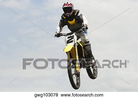 Low angle view of a motocross rider performing a jump on a motorcycle View Large Photo Image Stock Photo - Low angle view of a motocross rider performing a jump on a motorcycle. Fotosearch