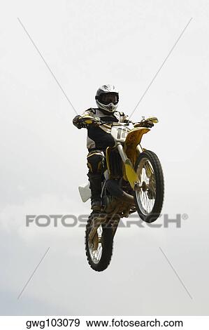 Low angle view of a motocross rider performing a jump on a motorcycle View Large Photo Image Stock Photo - Low angle view of a motocross rider performing a jump on a motorcycle. Fotosearch