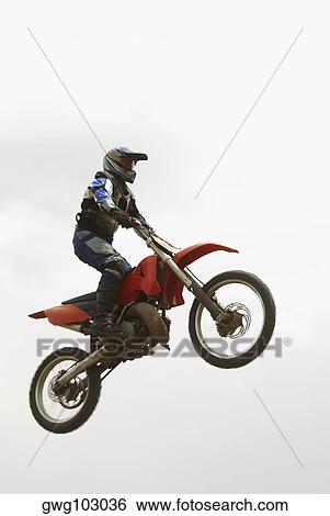 Low angle view of a motocross rider performing a jump on a motorcycle View Large Photo Image Stock Photograph - Low angle view of a motocross rider performing a jump on a motorcycle. Fotosearch