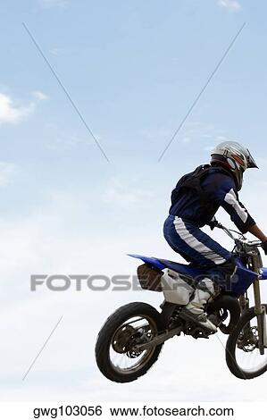 Low angle view of a motocross rider performing a jump on a motorcycle View Large Photo Image Stock Photograph - Low angle view of a motocross rider performing a jump on a motorcycle. Fotosearch