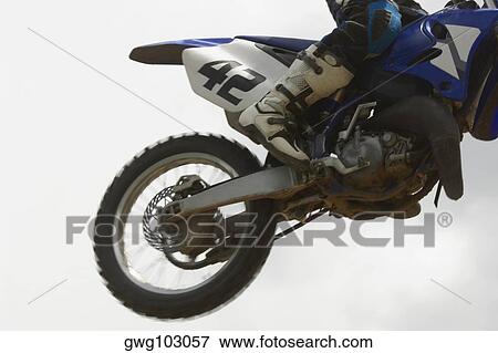 Low section view of a motocross rider performing jump on a motorcycle View Large Photo Image Stock Photo - Low section view of a motocross rider performing jump on a motorcycle. Fotosearch
