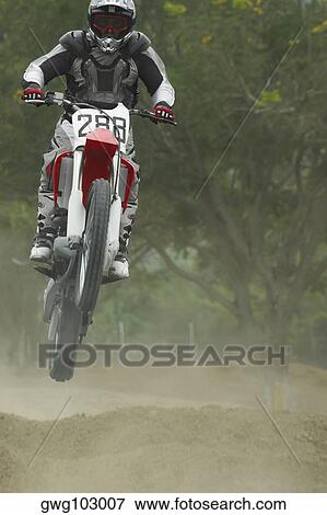 Motocross rider performing a jump on a motorcycle View Large Photo Image Stock Photo - Motocross rider performing a jump on a motorcycle. Fotosearch