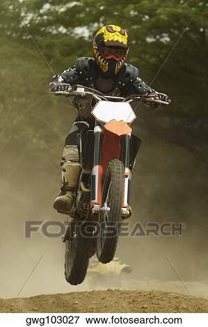 Motocross rider performing a jump on a motorcycle View Large Photo Image Stock Photo - Motocross rider performing a jump on a motorcycle. Fotosearch