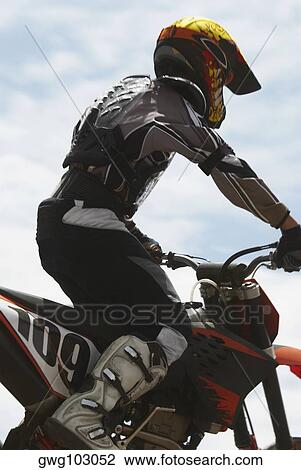 Stock Image - Side profile of a motocross rider riding a motorcycle. Fotosearch