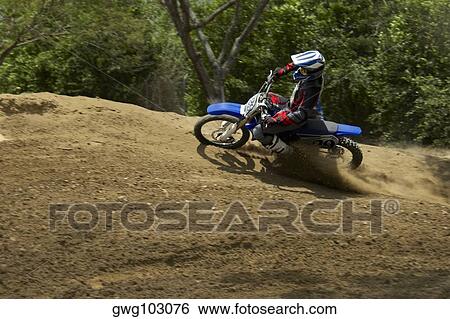 Stock Photograph - Side profile of a motocross rider riding a motorcycle. Fotosearch