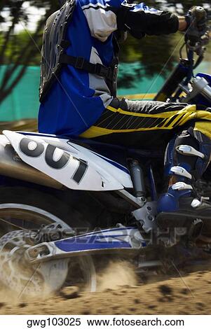 Stock Photography - Side profile of a motocross rider riding a motorcycle. Fotosearch