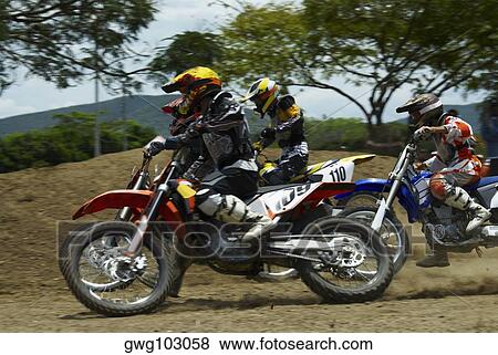 Three motocross riders riding motorcycles on a dirt road View Large Photo Image Stock Photo - Three motocross riders riding motorcycles on a dirt road. Fotosearch