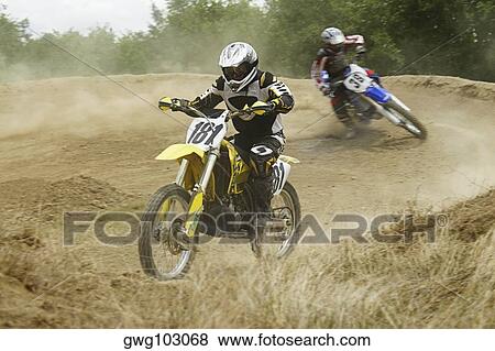 Two motocross riders riding motorcycles on a dirt road View Large Photo Image Stock Photo - Two motocross riders riding motorcycles on a dirt road. Fotosearch