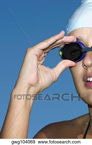 Close-up of a young woman adjusting her swimming goggles View Large Photo Image Stock Photo - Close-up of a young woman adjusting her swimming goggles. Fotosearch