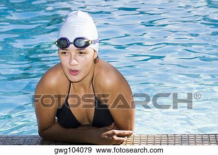 Stock Photo - Close-up of a young woman leaning at the edge of a swimming pool. Fotosearch