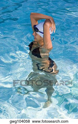 High angle view of a young woman standing in a swimming pool and smiling View Large Photo Image Stock Photo - High angle view of a young woman standing in a swimming pool and smiling. Fotosearch
