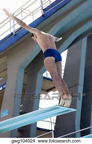 Low angle view of a mid adult man preparing to back dive from a diving board View Large Photo Image Picture - Low angle view of a mid adult man preparing to back dive from a diving board. Fotosearch