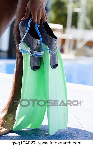 Low section view of a man holding a pair of flippers and standing at the poolside View Large Photo Image Stock Photo - Low section view of a man holding a pair of flippers and standing at the poolside. Fotosearch