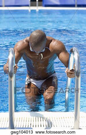 Stock Image - Mid adult man getting off a swimming pool. Fotosearch