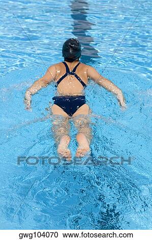 Rear view of a young woman swimming in a swimming pool View Large Photo Image Stock Image - Rear view of a young woman swimming in a swimming pool. Fotosearch
