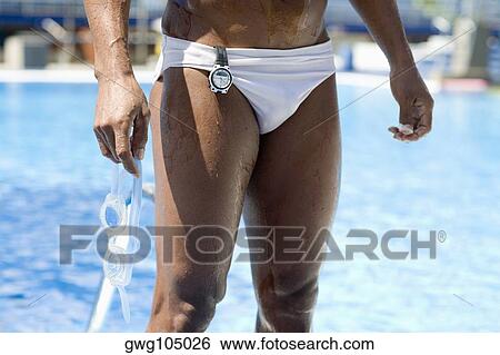 Mid section view of a man holding swimming goggles and standing at the poolside View Large Photo Image Stock Photograph - Mid section view of a man holding swimming goggles and standing at the poolside. Fotosearch