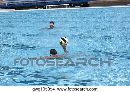 Picture - Two young men playing water polo in a swimming pool. Fotosearch
