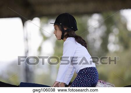 Stock Photo - Side profile of a girl riding a horse. Fotosearch