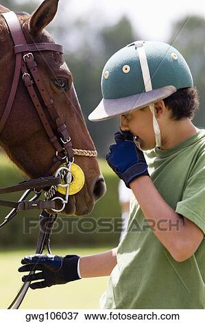 Teenage boy standing with a horse View Large Photo Image Stock Photo - Teenage boy standing with a horse. Fotosearch