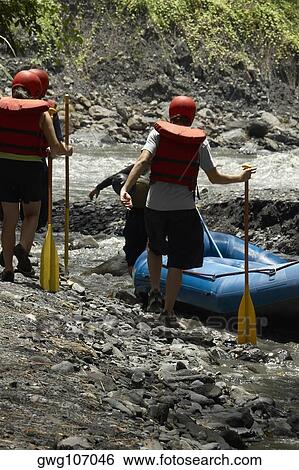 Four people walking towards an inflatable raft at a riverside View Large Photo Image Stock Photograph - Four people walking towards an inflatable raft at a riverside. Fotosearch