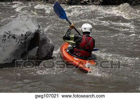 Stock Image - Rear view of a person kayaking in a river. Fotosearch