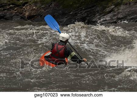 Stock Image - Rear view of a person kayaking in a river. Fotosearch
