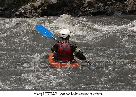 Stock Image - Rear view of a person kayaking in a river. Fotosearch