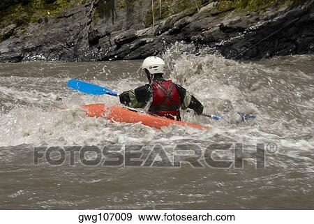 Stock Photo - Rear view of a person kayaking in a river. Fotosearch