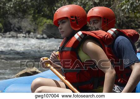 Side profile of a young man and a young woman rafting in a river View Large Photo Image Picture - Side profile of a young man and a young woman rafting in a river. Fotosearch