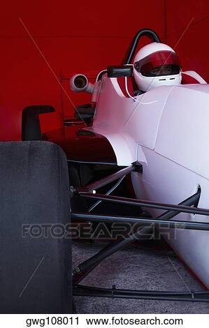 Stock Image - Racecar driver in a racecar under a shed. Fotosearch