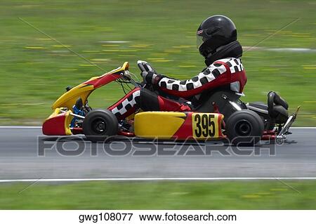 Stock Photo - Side profile of a person go-carting on a motor racing track. Fotosearch