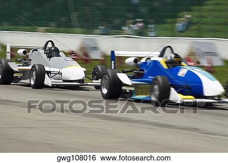 Two racecars racing on a motor racing track View Large Photo Image Stock Photograph - Two racecars racing on a motor racing track. Fotosearch