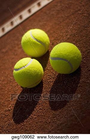 Stock Image - Close-up of three tennis balls in a court. Fotosearch