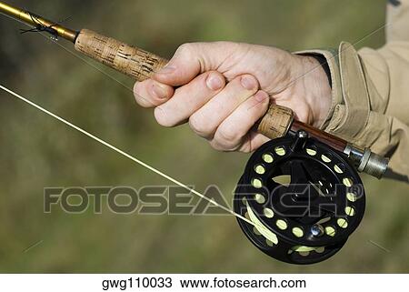 Stock Image - Close-up of a man's hand holding a fishing rod. Fotosearch
