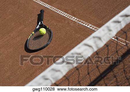 Stock Photo - High angle view of a tennis ball on a racket in a court. Fotosearch