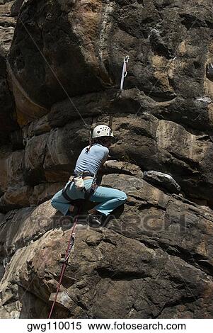 Low angle view of a female rock climber scaling a rock face View Large Photo Image Stock Photography - Low angle view of a female rock climber scaling a rock face. Fotosearch