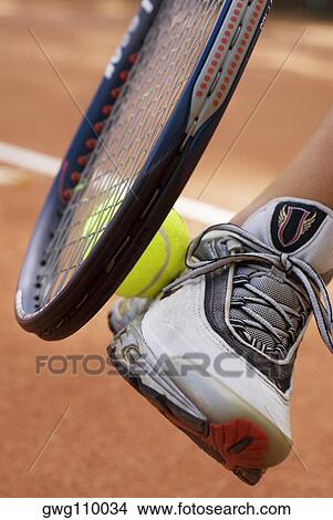 Low section view of a woman with a tennis racket and a tennis ball View Large Photo Image Picture - Low section view of a woman with a tennis racket and a tennis ball. Fotosearch