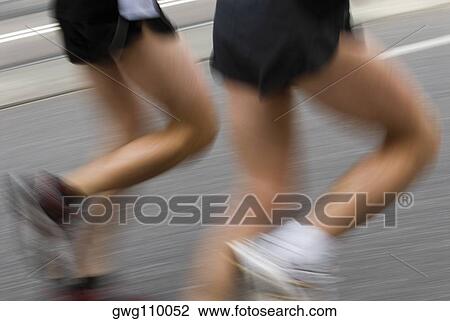 Stock Image - Low section view of two male athletes running on a running track. Fotosearch