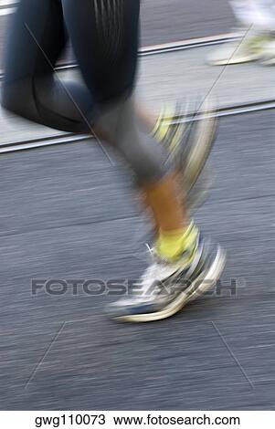 Stock Image - Low section view of two male athletes running on a running track. Fotosearch