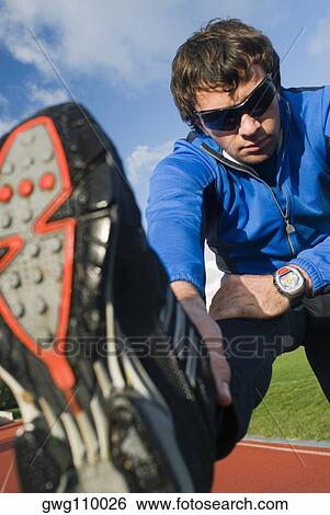 Stock Photograph - Mid adult man exercising on a running track. Fotosearch